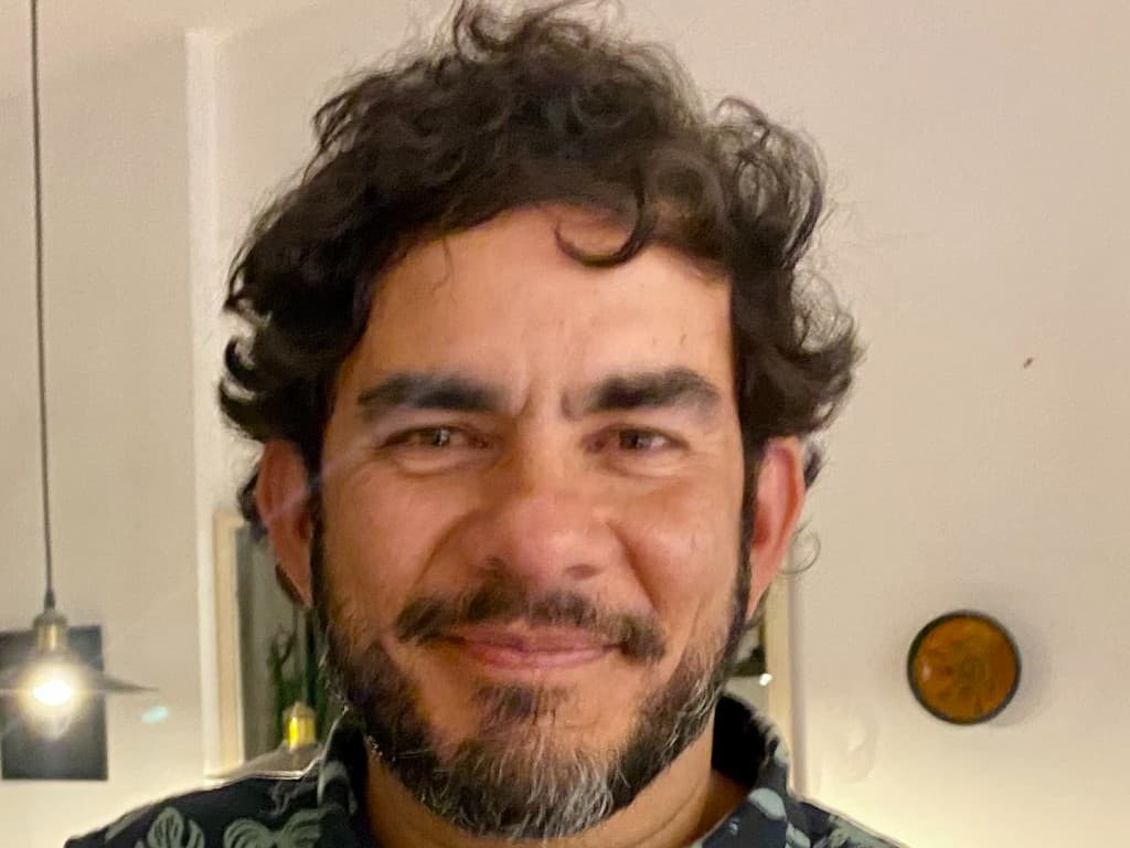 Ricardo Paes, fundador da Kodigo, sorrindo em retrato profissional com camisa escura estampada.